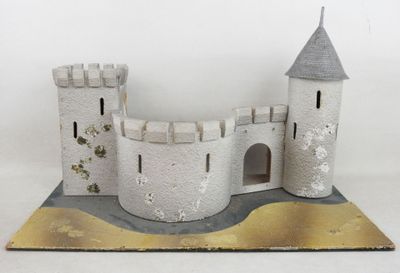 une petite maquette de château posée sur une surface blanche