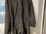 une veste noire accrochée à un mur, avec un tableau en arrière-plan