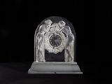 a glass clock with angels on it sitting on a table