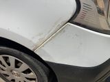 a white car that has been damaged and is parked on the street