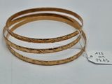 trois bracelets rigides en or avec une étiquette de prix sur un fond blanc