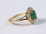 a close up of a gold ring with a green stone and diamonds