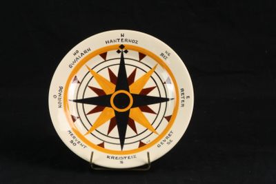 une assiette blanche ornée d'un motif représentant un compas jaune et noir