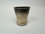 un vase noir et argent posé sur une surface blanche