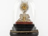 une horloge posée sur un socle, sous un dôme en verre