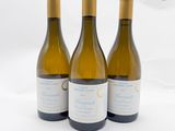trois bouteilles de vin posées sur une table blanche