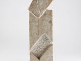 sculpture représentant un bloc de pierre surmonté d'une feuille, posée sur une surface blanche
