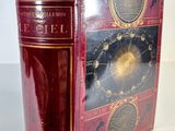 an old book with a red cover sitting on top of a white table
