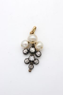 un gros plan d'un pendentif en perle et diamants sur une surface blanche