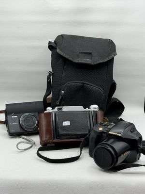 un appareil photo, un étui pour appareil photo, un appareil photo et d'autres objets posés sur une table