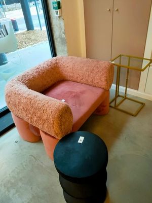 une chaise rose et un tabouret noir dans une pièce