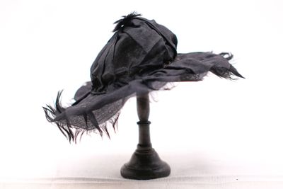 un chapeau noir posé sur un support noir, sur fond blanc