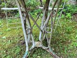 an old metal table with a rusted top sitting in the grass