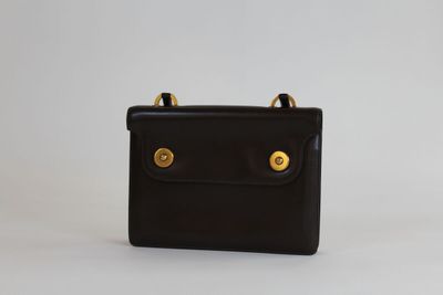 un petit sac à main noir orné de deux boutons dorés sur le devant