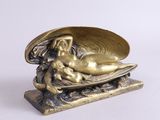 une statue en or représentant une femme allongée sur un coquillage