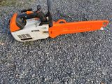 an orange and black chainsaw sitting on top of a gravel road
