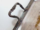 an antique silver plate with a handle on a white wall