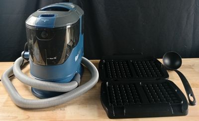 un aspirateur bleu et un gaufrier posés sur une table en bois