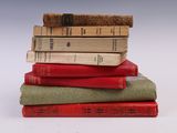 several old books stacked on top of each other on a white surface
