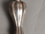 un objet en argent posé sur une table, muni d'une chaîne