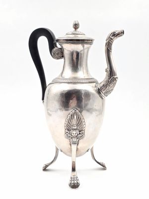 une théière ancienne en argent, dotée d'une anse noire et posée sur un socle