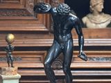 une statue représentant un homme tenant une raquette de tennis posée sur une table