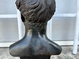 bronze bust of a boy on a pedestal in front of a window