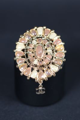 CHANEL. Broche en métal doré figurant une rosace ornée de ca…