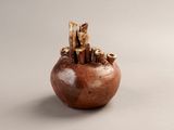 a small brown vase with a bunch of small things inside of it