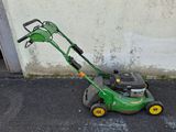 a green lawn mower that is sitting on the ground