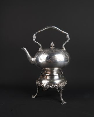 a silver teapot on a stand with a handle