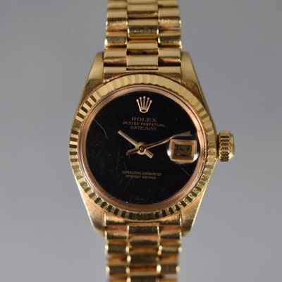 a close up of a gold wrist watch with a black dial