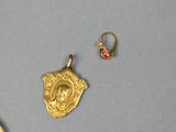 three pieces of jewelry including a gold pendant, a red bead, and a pair of earrings
