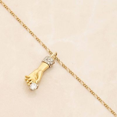 a close up of a gold necklace with a hand holding a diamond