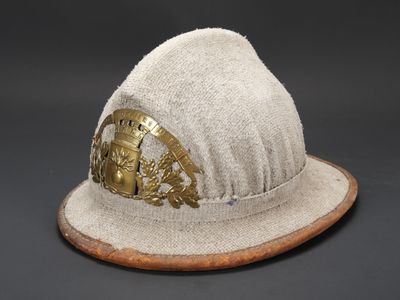 bonnet en laine beige orné d'une boucle en laiton posée sur une base en bois