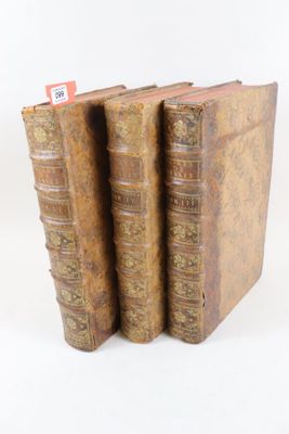 trois vieux livres sont empilés sur une surface blanche
