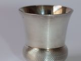 une tasse en argent posée sur une surface blanche