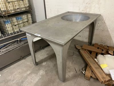 une table en béton sur laquelle se trouve un évier, dans une pièce