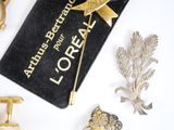 a black book with a gold ribbon and some gold brooches