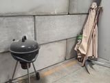 a black grill sitting on a concrete floor next to a brick wall