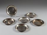 six assiettes en métal argenté et un plat en argent sur un support