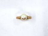 a close up of a pearl ring on a white surface