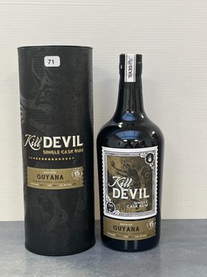 une bouteille de « Red Devil Guyana » avec son coffret, posée sur une table devant un mur blanc