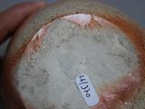someone is holding a brown and white vase with a tag on it
