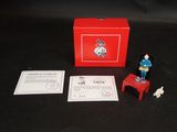 une petite figurine représentant un homme debout sur une chaise rouge