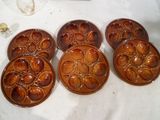 six assiettes en céramique brune avec des motifs, posées sur une table