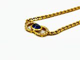 a close up of a gold chain with a blue stone on it