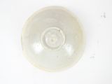 a white bowl on a white surface with a small amount of dirt
