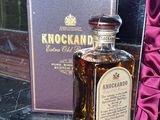a bottle of liquor sitting next to a box on a window sill