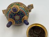 a small blue and gold teapot next to a small gold cup